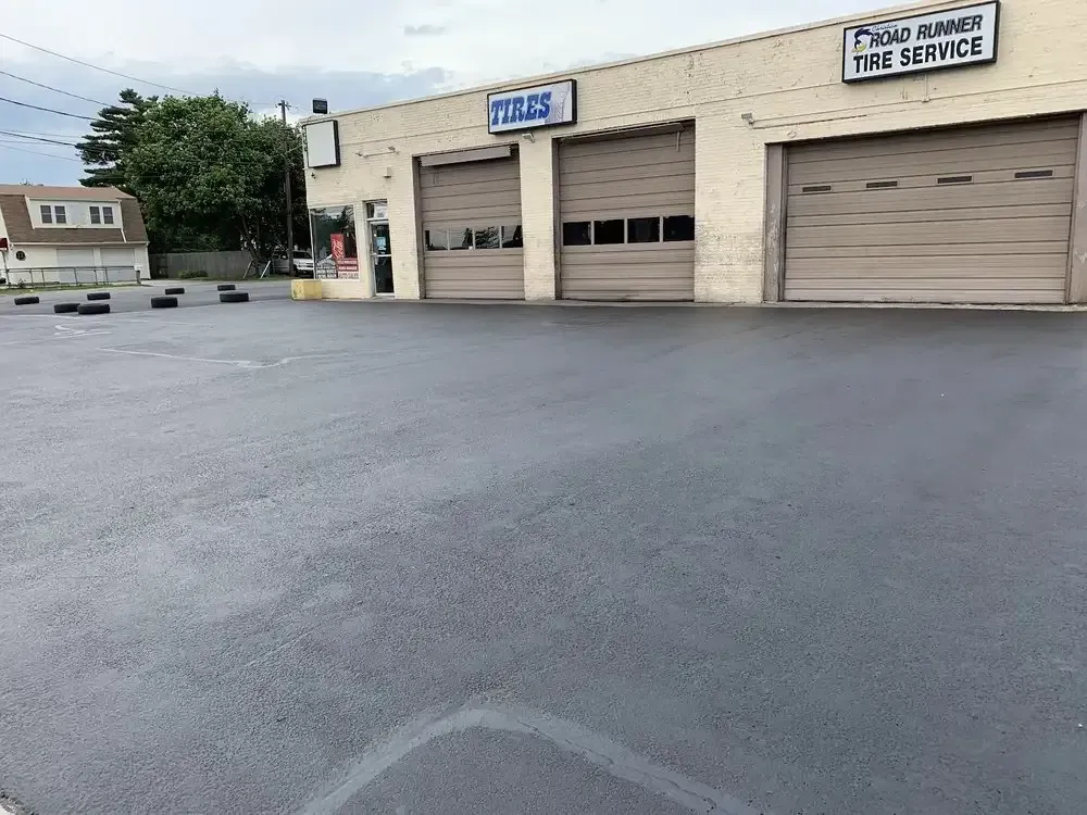 Former Road Runner Tire Service sign above the shop's tan bay doors and parking lot