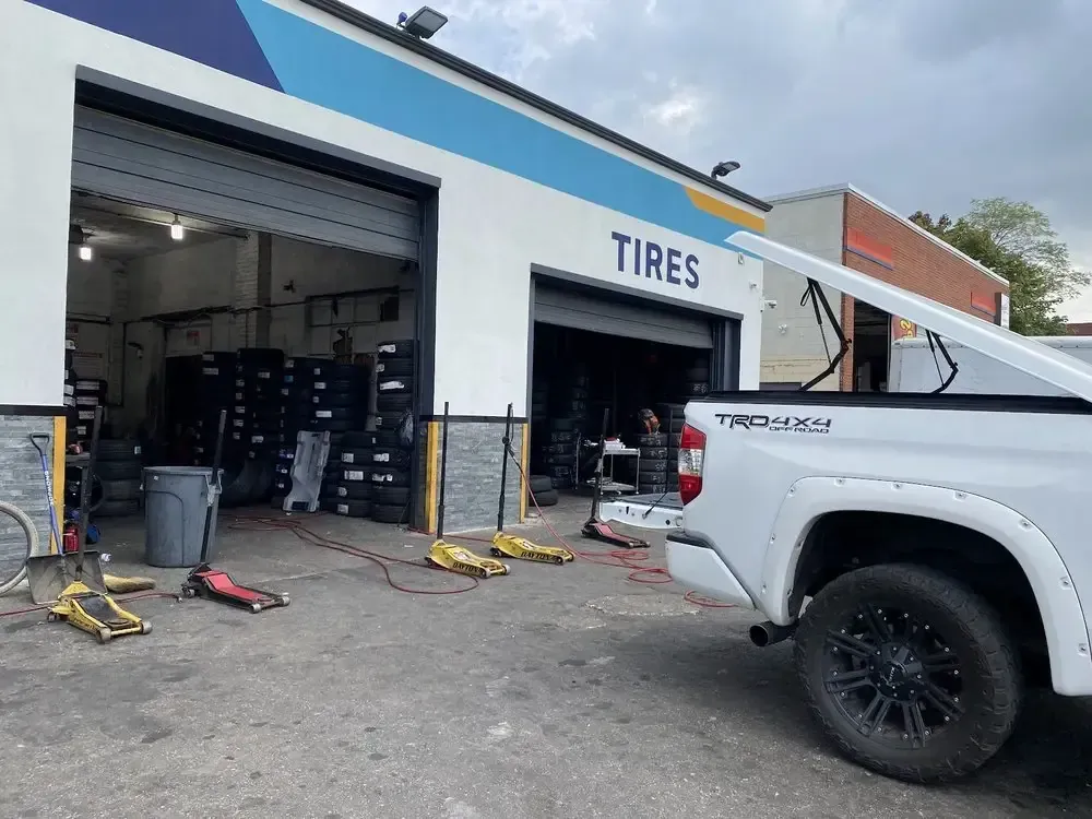 Open bays at Christian’s Road Runner Tire Service with tire racks, floor jacks and a pickup