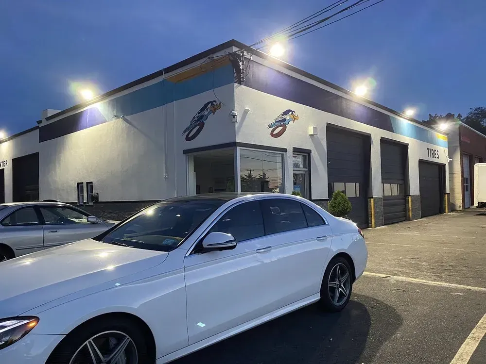 Christian’s Road Runner Tire Service at dusk with roadrunner murals and a white sedan outside