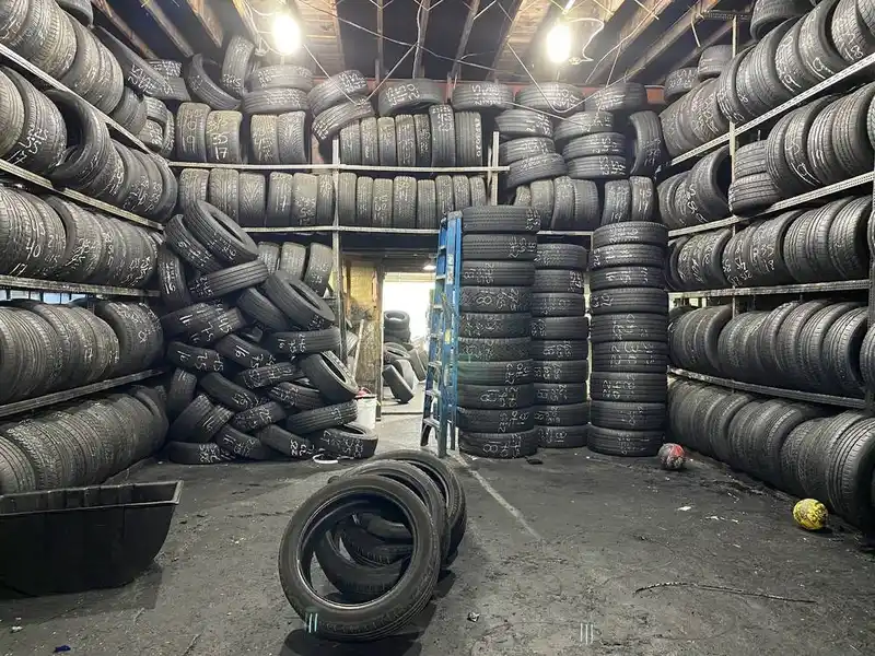 Used tires stacked high on racks and the floor inside the tire shop