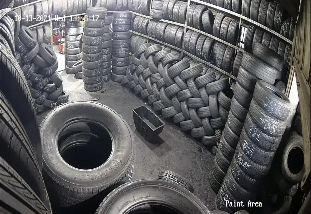 Used tires stacked in rows filling a storage room, seen from a security camera